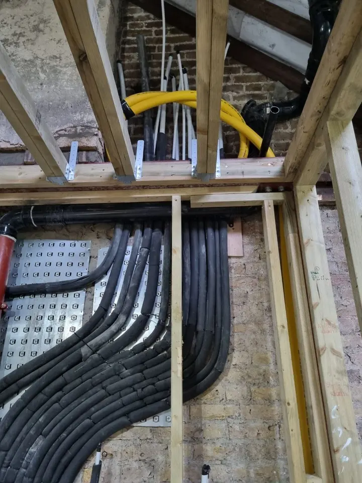 Insulated pipe runs along a brick wall with a gas pipe above
